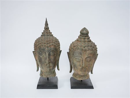 Lotto di due teste di Buddha in bronzo, su basi in legno (difetti) (h. max 45...