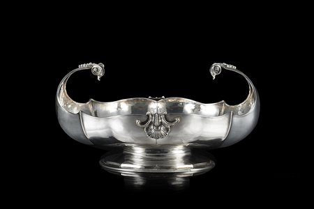 Centrotavola in argento di forma ovale, baccellato e costolato, con prese a...