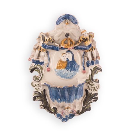 Manifattura faentina attiva nell'ultimo quarto del XVIII secolo ( - ) 
Acquasantiera in maiolica con decori a rilievo recante un medaglione centrale con l'effigie della Vergine con il Bambino. 
 cm 31x20