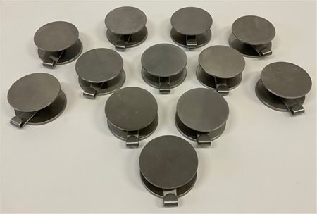 Gruppo di dodici appendiabiti in metallo spazzolato. Italia, anni '70. (d cm 8)
