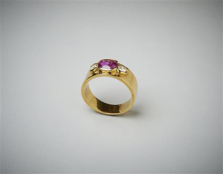  . - Anello a fascia in oro giallo 750/1000 con rubino cenrrale ovale di 1.30 ct. circa e due diamanti di 0.40 ct. circa totali.