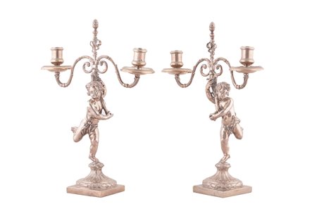  
Coppia di candelieri in argento a due fuochi a forma di putti , XX secolo. 
 cm 32x24