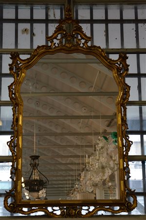 Grande specchiera in legno intagliato e dorato, decorata a volute e piccole...