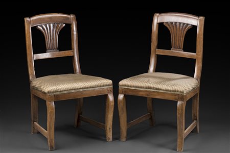 Coppia di sedie in legno chiaro di forma mossa con schienale intagliato...