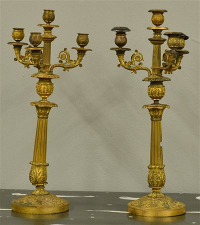 Coppia di candelieri a quattro fiamme in metallo dorato, decorato a motivi...