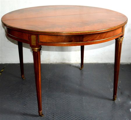 Tavolo tondo allungabile in mogano decorato con profili in ottone, gambe...