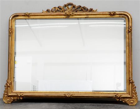 Specchiera rettangolare in legno dorato con cimasa intagliata e traforata....