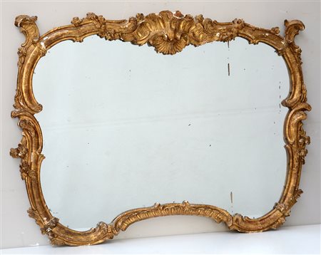 Specchiera di forma mossa in legno dorato intagliata a volute e motivi...