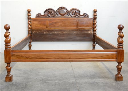 Letto in noce con testata decorata da cimasa intagliata e traforata a volute....