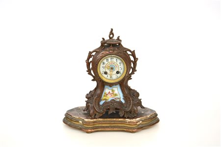 Pendola in bronzo di forma mossa, fronte con inserto in porcellana policroma...