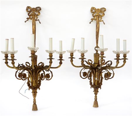 Coppia di appliques a cinque fiamme in metallo dorato con braccia sagomate,...