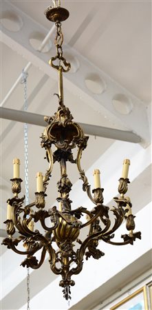 Lampadario a otto luci in bronzo con braccia sagomate decorate a motivi...
