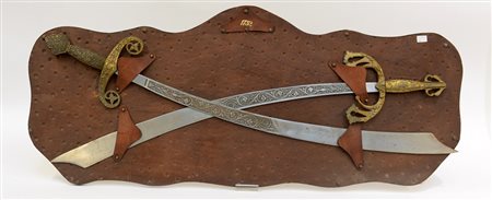 Due spade incise a volute, montate su pannello in cuoio