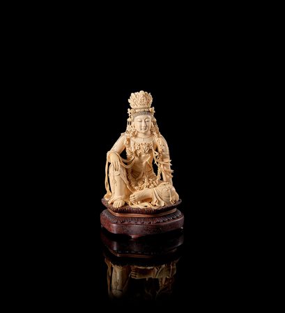 Guanyin in avorio, raffigurata seduta in posizione lalitasana, indossa vesti...