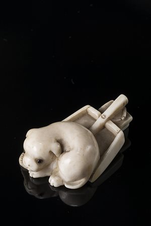 Netsuke in avorio raffigurante cagnolino seduto su paletta Giappone, sec. XIX...