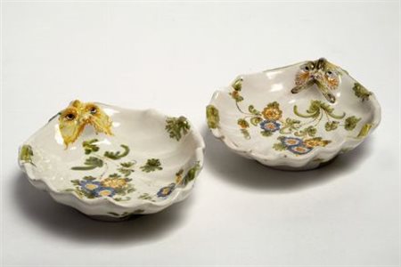 Coppia di raviere a valva con mascheroni e decori a mazzetti su fondo bianco,...