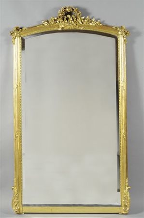 Specchiera in legno dorato, con cornice scanalata, cimasa intagliata con...