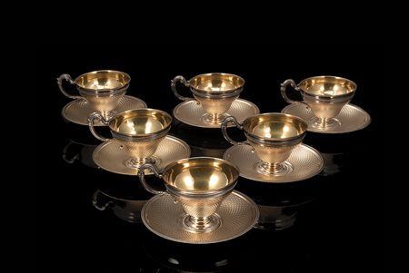 Lotto composto da sei tazze con piattini in metallo argentato, decorati a...