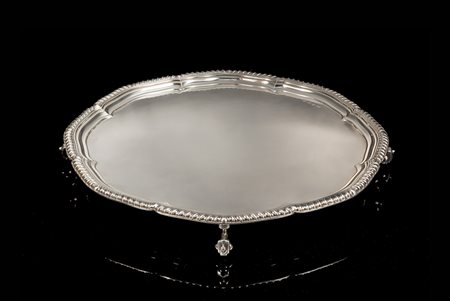 Salver in argento di forma circolare sagomata con fondo liscio e bordura...