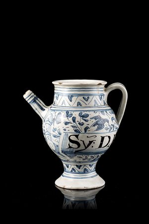 Versatoio in maiolica con ansa a nastro. Decorazione in "stile calligrafico"...