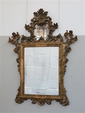 Specchiera rettangolare in legno dorato con cimasa e fregi intagliati e...