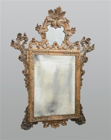 Specchiera rettangolare in legno dorato con cimasa e fregi intagliati e...