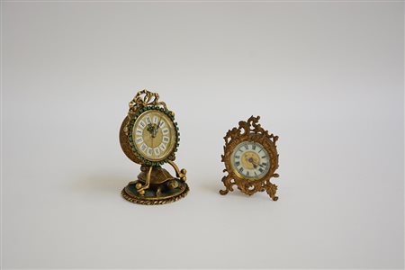Lotto composto da due sveglie da tavolo in metallo dorato, una decorata a...