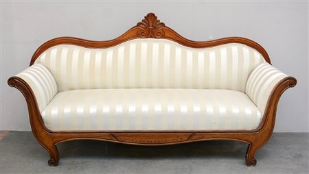 Divano a barca in noce con schienale sagomato centrato da fregio intagliato....