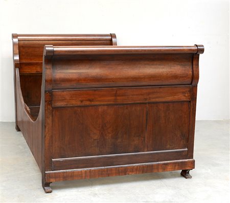 Letto a barca da parete in noce. Montanti intagliati a volute e fregi, base a...