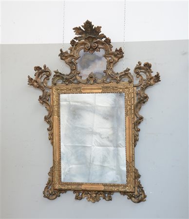 Specchiera rettangolare in legno dorato con cimasa e fregi intagliati e...