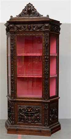 Vetrina di forma sagomata in noce con cimasa intagliata a volute, fascia...