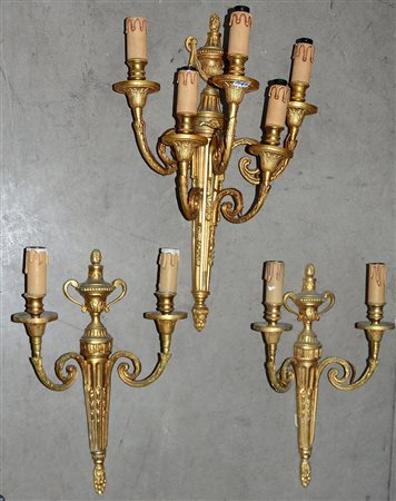 Lotto composto da due applique a due luci e una cinque luci in bronzo dorato...