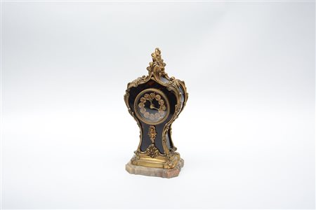 Orologio in bronzo e finta tartaruga decorata a motivi vegetali e volute,...