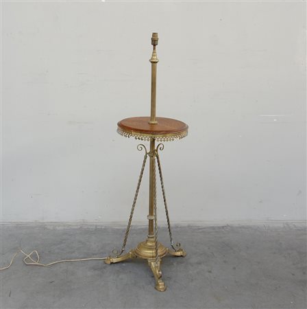 Una lampada da terra in ottone con fusto tornito e pianetto in legno, piedi...