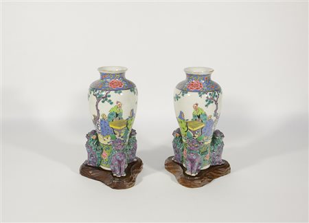 Coppia di vasi in porcellana policroma decorati con figure e basi in rilievo...
