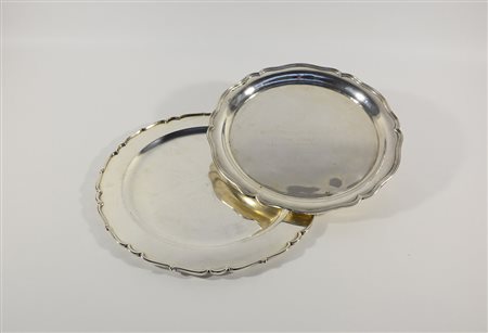 Due piatti in argento di forma circolare sagomata, con fondo liscio di cui...