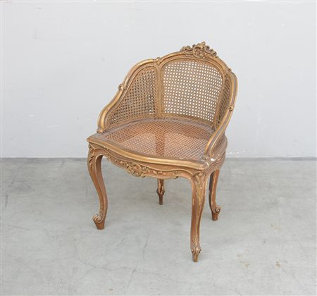 Poltroncina a pozzetto in legno dorato intagliato a motivi floreali,...