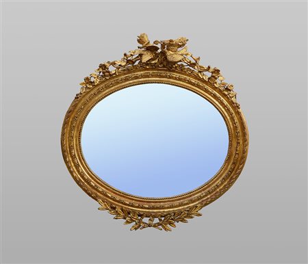 Specchiera ovale in legno dorato e intagliato, parte inferiore decorata da un...