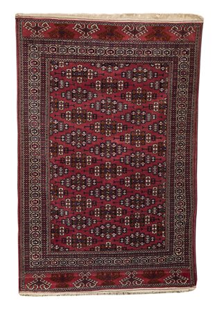 Tappeto a fondo rosso, decorato a motivi geometrici nei toni del bianco e del...