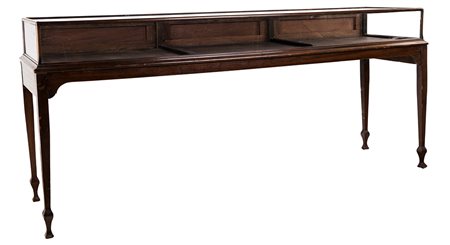 Grande tavolo espositore in noce, con piano rettangolare e fascia in vetro,...