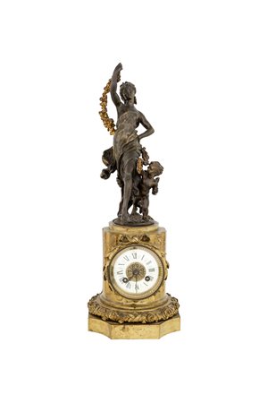 Orologio in bronzo dorato e brunito, con cassa a rocchio di colonna scanalata...