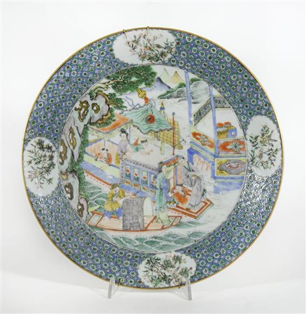 Piatto in porcellana policroma decorato con scene orientali. Diam. cm. 35.