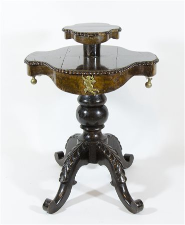 Tavolino in legno scuro con piano sagomato e alzata centrale.