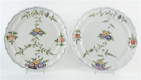 Coppia di grandi piatti in maiolica a smalti policromi con decori floreali....