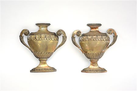 Coppia di fregi in argento sbalzato a forma di vasi biansati con decoro a...