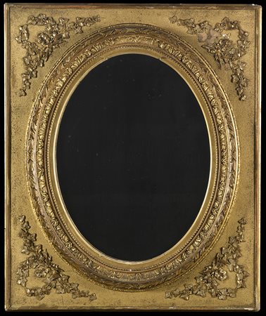 Specchiera ovale in legno intagliato e dorato, la parte centrale a rilievo...