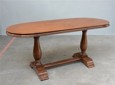 Tavolo ovale con gambe tornite poggianti su piedi sagoamti riuniti da...