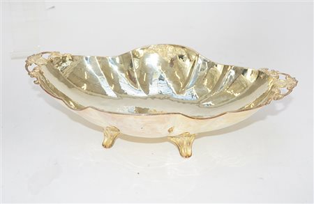 Centrotavola in argento di forma ovale, sagomata e a quattro piedini. Italia,...