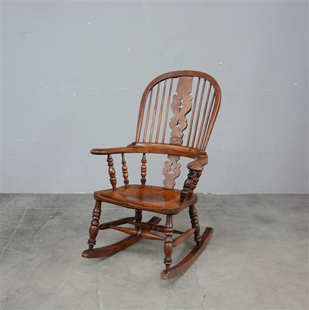 Poltrona a dondolo con schienale traforato e decorato a listelli. Braccioli...