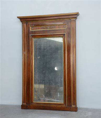 Caminiera in noce di forma architettonica con profili in ottone e fascia...